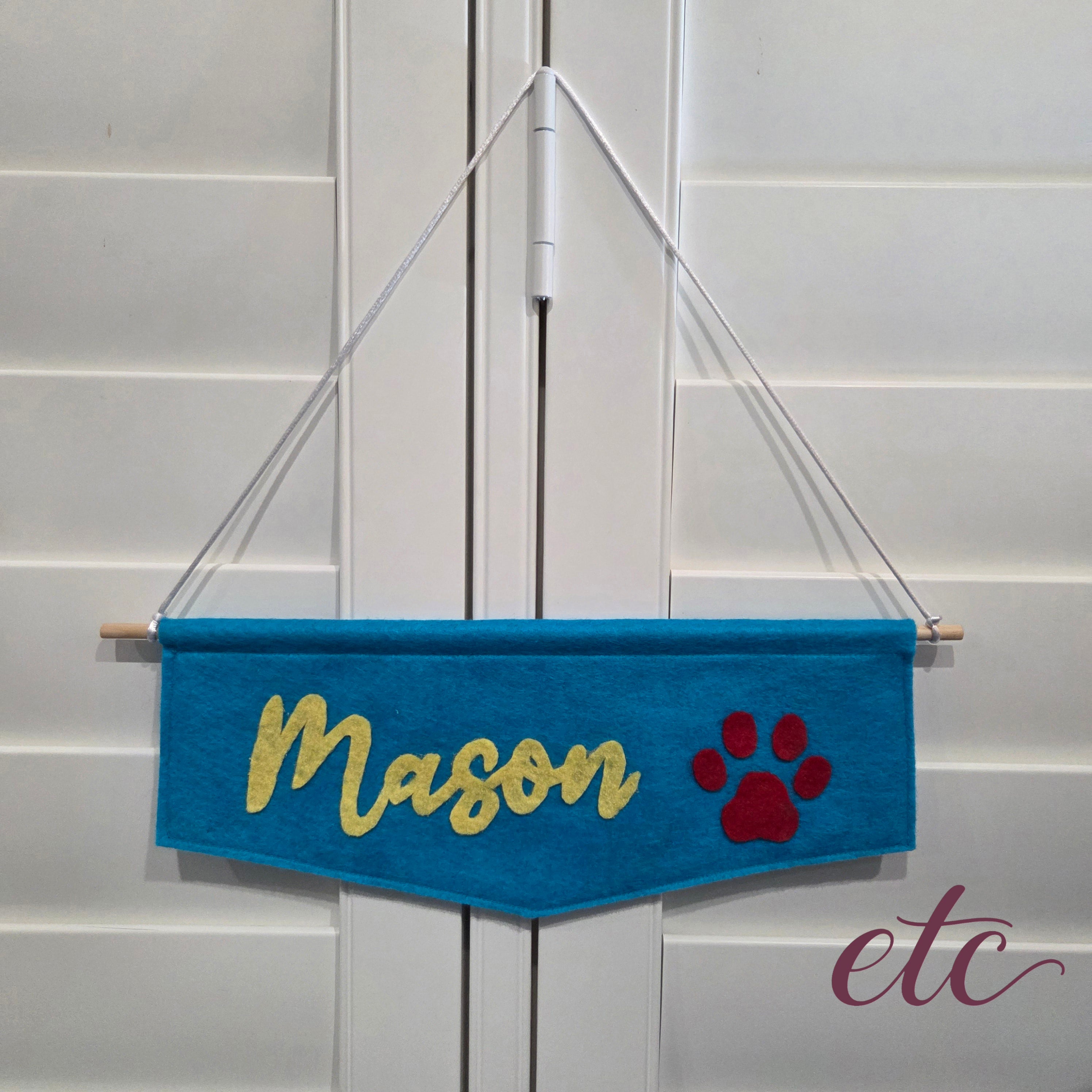 Blue felt banner with 'Mason' and a red paw print on a white background