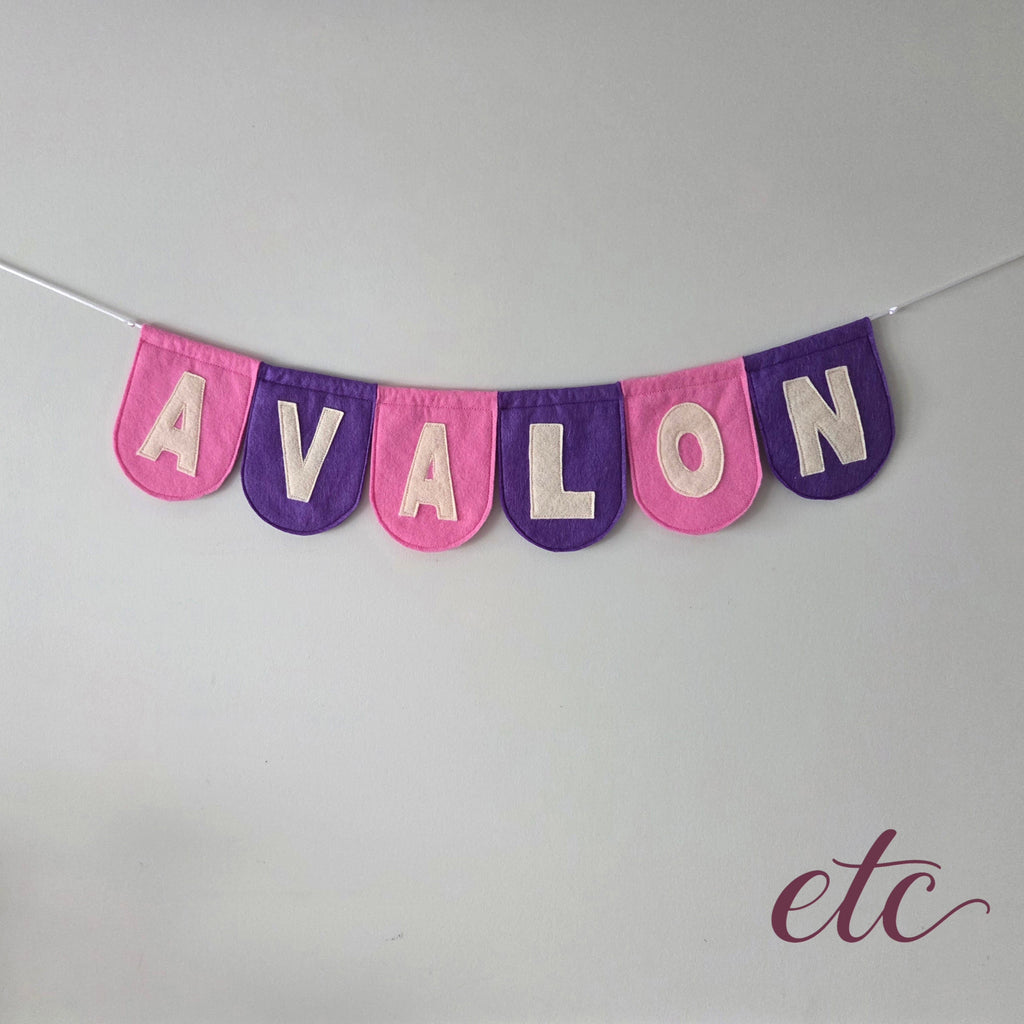 Personalised felt bunting / garland with 'Avalon' letters on a plain background