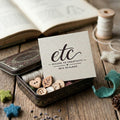 Small tin box with decorative items and a card on a wooden surface, featuring Gift card  Escape to Creativity New Zealand'.