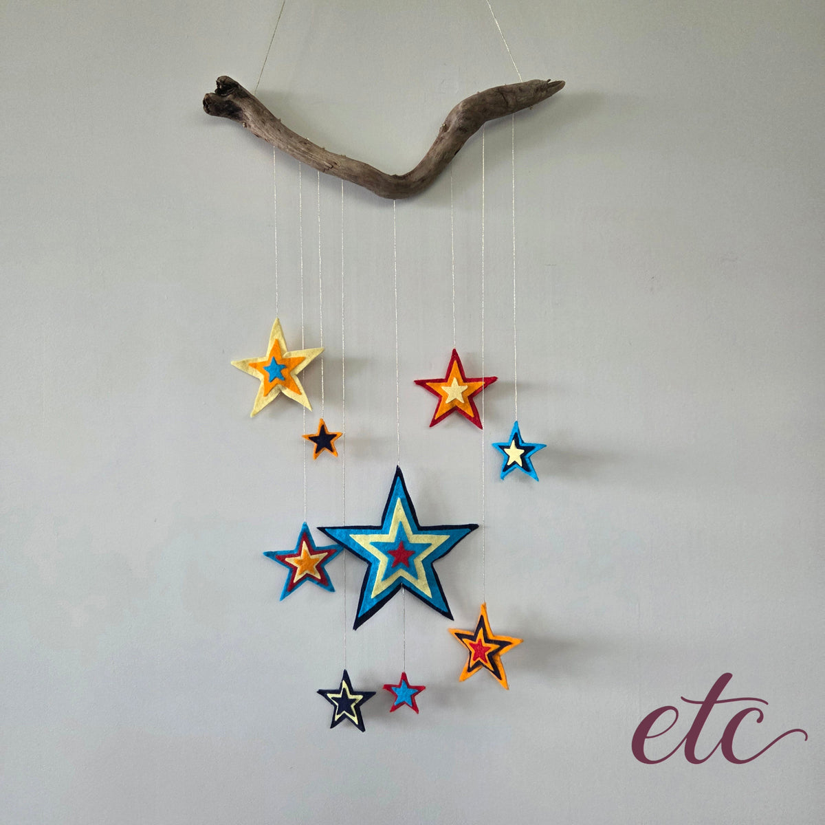 Dreamcatcher with different size stars to celebrate Matariki and featuring colours as navy, turqoise, yellow, orange and red.
